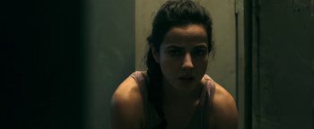 Movie still from “No One Gets Out Alive” (2021), directed by Santiago Menghini – A young woman is looking at the camera; Close Up shot, Over the shoulder angle