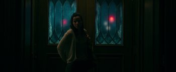 Movie still from “No One Gets Out Alive” (2021), directed by Santiago Menghini – A woman standing in front of a stained glass window; Medium shot, Over the shoulder angle