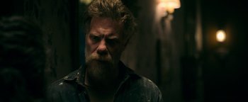 Movie still from “No One Gets Out Alive” (2021), directed by Santiago Menghini – A man with a long beard and a mustache; Close Up shot, Low angle