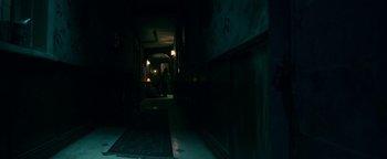 Movie still from “No One Gets Out Alive” (2021), directed by Santiago Menghini – A person is walking down a hallway at night; Wide shot, High angle