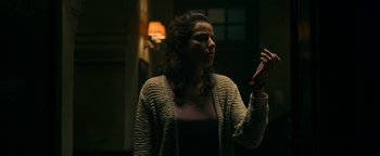 Movie still from “No One Gets Out Alive” (2021), directed by Santiago Menghini – A woman is holding her hands up in the dark; Medium shot, Low angle