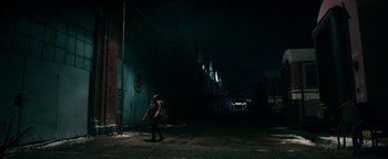 Movie still from “No One Gets Out Alive” (2021), directed by Santiago Menghini – A person walking in the dark near a building; Extreme Wide shot, Low angle