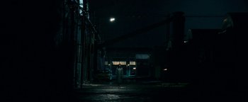 Movie still from “No One Gets Out Alive” (2021), directed by Santiago Menghini – A person standing in a dark alley at night; Extreme Wide shot, Low angle