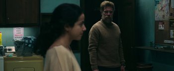 Movie still from “No One Gets Out Alive” (2021), directed by Santiago Menghini – A man and a woman standing next to each other in a room; Medium shot, Over the shoulder angle