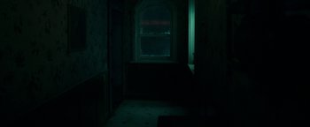 Movie still from “No One Gets Out Alive” (2021), directed by Santiago Menghini – A dark room with a window lit by a red light; Extreme Wide shot, High angle