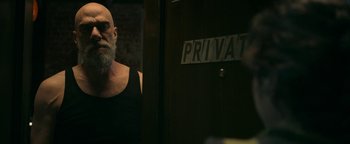 Movie still from “No One Gets Out Alive” (2021), directed by Santiago Menghini – A man with a beard is standing next to a private sign; Medium shot, Over the shoulder angle