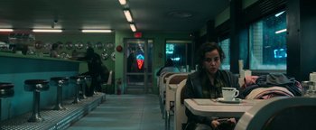 Movie still from “No One Gets Out Alive” (2021), directed by Santiago Menghini – A woman sitting at a table in a restaurant; Medium shot, High angle