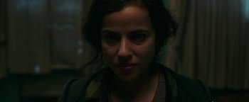 Movie still from “No One Gets Out Alive” (2021), directed by Santiago Menghini – A woman's face in the dark; Close Up shot, Over the shoulder angle