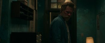 Movie still from “No One Gets Out Alive” (2021), directed by Santiago Menghini – A man standing in front of an oven in a dark room; Medium shot, Over the shoulder angle