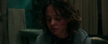 Movie still from “No One Gets Out Alive” (2021), directed by Santiago Menghini – A young woman is crying in a dark room; Close Up shot, Over the shoulder angle
