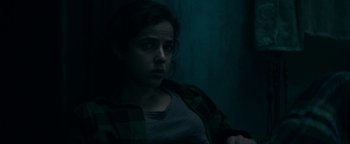 Movie still from “No One Gets Out Alive” (2021), directed by Santiago Menghini – A woman in a plaid shirt looking at the camera; Close Up shot, Over the shoulder angle