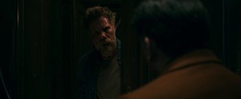 Movie still from “No One Gets Out Alive” (2021), directed by Santiago Menghini – A man with a beard looking at himself in the mirror; Medium shot, Over the shoulder angle