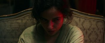 Movie still from “No One Gets Out Alive” (2021), directed by Santiago Menghini – A person with a red light in the background; Close Up shot, High angle