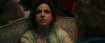 Movie still from “No One Gets Out Alive” (2021), directed by Santiago Menghini – A woman sitting on a couch with her hands clasped in front of her face; Close Up shot, High angle
