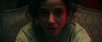 Movie still from “No One Gets Out Alive” (2021), directed by Santiago Menghini – A woman's face in a dark room; Close Up shot, Low angle