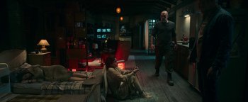 Movie still from “No One Gets Out Alive” (2021), directed by Santiago Menghini – A man and a woman are sitting on the floor in a living room; Wide shot, High angle