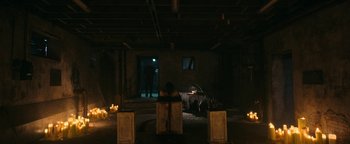 Movie still from “No One Gets Out Alive” (2021), directed by Santiago Menghini – A person sitting in a dark room next to a window; Extreme Wide shot, Over the shoulder angle