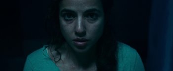 Movie still from “No One Gets Out Alive” (2021), directed by Santiago Menghini – A woman's face in the dark; Close Up shot, Overhead angle