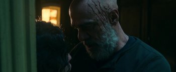 Movie still from “No One Gets Out Alive” (2021), directed by Santiago Menghini – A man with a beard is holding a woman; Close Up shot, Over the shoulder angle