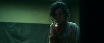 Movie still from “No One Gets Out Alive” (2021), directed by Santiago Menghini – A woman in a white shirt with blood on her face; Close Up shot, Low angle