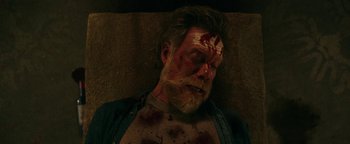 Movie still from “No One Gets Out Alive” (2021), directed by Santiago Menghini – A person with blood all over his face; Close Up shot, Overhead angle