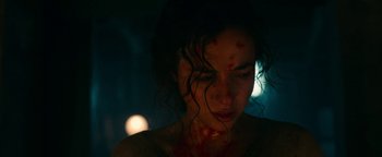 Movie still from “No One Gets Out Alive” (2021), directed by Santiago Menghini – A person with blood all over her face; Close Up shot, High angle