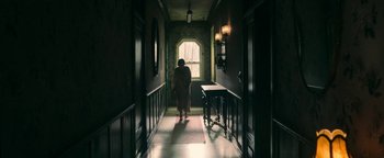 Movie still from “No One Gets Out Alive” (2021), directed by Santiago Menghini – A woman walking down a hallway in a dark room; Wide shot, Low angle