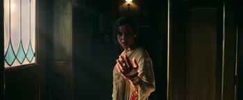 Movie still from “No One Gets Out Alive” (2021), directed by Santiago Menghini – A woman with blood on her hands is standing in a dark room; Medium shot, Low angle