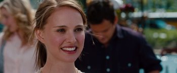 Movie still from “No Strings Attached” (2011), directed by Ivan Reitman – A person smiling with a man in the background; Close Up shot, Over the shoulder angle