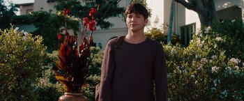 Movie still from “No Strings Attached” (2011), directed by Ivan Reitman – A young man standing in front of some bushes; Medium shot, Over the shoulder angle