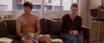 Movie still from “No Strings Attached” (2011), directed by Ivan Reitman – A man and a woman sitting on a couch; Medium shot, Over the shoulder angle