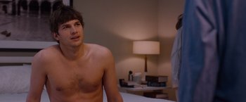 Movie still from “No Strings Attached” (2011), directed by Ivan Reitman – A man sitting on top of a bed next to a lamp; Medium shot, Over the shoulder angle
