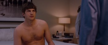 Movie still from “No Strings Attached” (2011), directed by Ivan Reitman – A man sitting on top of a bed next to another man; Medium shot, Over the shoulder angle