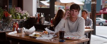 Movie still from “No Strings Attached” (2011), directed by Ivan Reitman – A man sitting at a table in front of a plate of food; Medium shot, Over the shoulder angle
