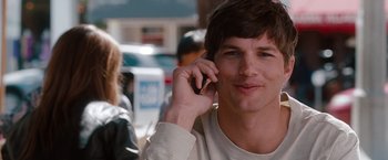 Movie still from “No Strings Attached” (2011), directed by Ivan Reitman – A man talking on a cell phone while standing on a sidewalk; Close Up shot, Over the shoulder angle
