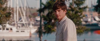 Movie still from “No Strings Attached” (2011), directed by Ivan Reitman – A young man standing in front of trees and a body of water; Close Up shot, Over the shoulder angle