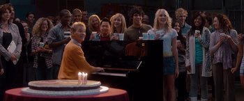 Movie still from “No Strings Attached” (2011), directed by Ivan Reitman – A group of people standing in front of a piano; Medium shot, Over the shoulder angle