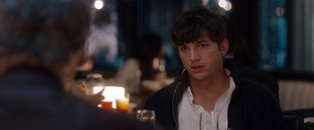 Movie still from “No Strings Attached” (2011), directed by Ivan Reitman – A man sitting in front of a table with a drink; Close Up shot, Over the shoulder angle