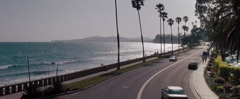 Movie still from “No Strings Attached” (2011), directed by Ivan Reitman – A car driving down a road next to a body of water; Extreme Wide shot, High angle