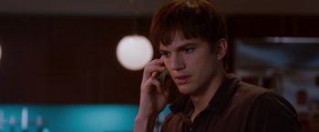 Movie still from “No Strings Attached” (2011), directed by Ivan Reitman – A man talking on a cell phone while wearing a brown shirt; Close Up shot, Over the shoulder angle