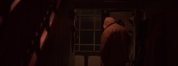 Movie still from “Nobody Knows I'm Here” (2020), directed by Gaspar Antillo – A person wearing a hooded jacket looking out of a window; Medium shot, Over the shoulder angle