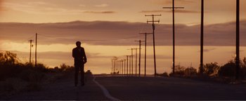 Movie still from “Nocturnal Animals” (2016), directed by Tom Ford – A man standing on the side of a road near power lines; Extreme Wide shot, Low angle