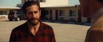 Movie still from “Nocturnal Animals” (2016), directed by Tom Ford – A person wearing a plaid shirt near a building; Close Up shot, Over the shoulder angle