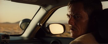 Movie still from “Nocturnal Animals” (2016), directed by Tom Ford – A man in a car looking into the side view mirror; Close Up shot, Over the shoulder angle