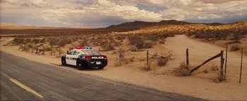 Movie still from “Nocturnal Animals” (2016), directed by Tom Ford – A police car parked on the side of the road; Extreme Wide shot, High angle