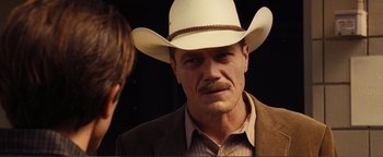 Movie still from “Nocturnal Animals” (2016), directed by Tom Ford – A man in a cowboy hat is looking at the camera; Close Up shot, Over the shoulder angle