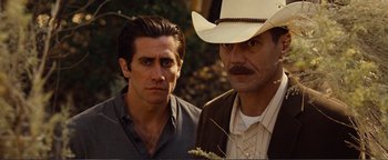 Movie still from “Nocturnal Animals” (2016), directed by Tom Ford – A man in a cowboy hat stands next to another man in a cowboy hat; Close Up shot, Low angle