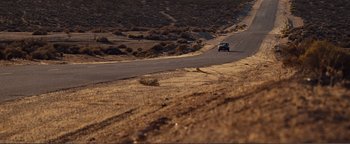 Movie still from “Nocturnal Animals” (2016), directed by Tom Ford – A car driving down a road in the middle of a desert; Extreme Wide shot, High angle