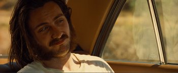 Movie still from “Nocturnal Animals” (2016), directed by Tom Ford – A man with long hair and a beard sitting in a car; Close Up shot, Over the shoulder angle