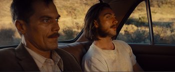 Movie still from “Nocturnal Animals” (2016), directed by Tom Ford – A man with long hair sitting next to another man in the back of a car; Close Up shot, Over the shoulder angle